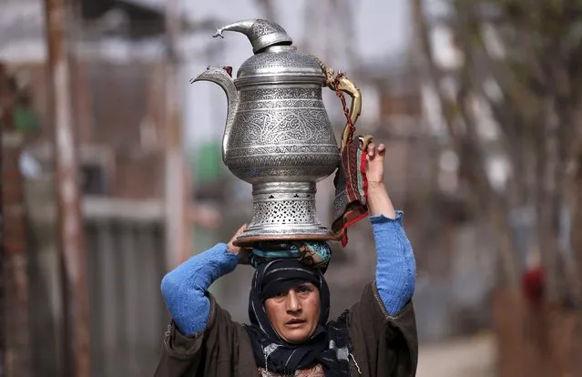 A Kashmiri woman carrying traditional teapot called a samovar on her head walks on a road in Srinagar March 23, 2016. (Photo by Danish Ismail/Reuters)