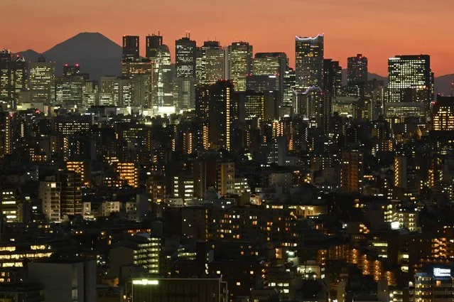 A general view shows Japan's highest mountain, Mt. Fuji (3,776m or 12,388 feet) and skyscrapers in Tokyo's Shinjuku area at sunset on March 18, 2024. (Photo by Kazuhiro Nogi/AFP Photo)