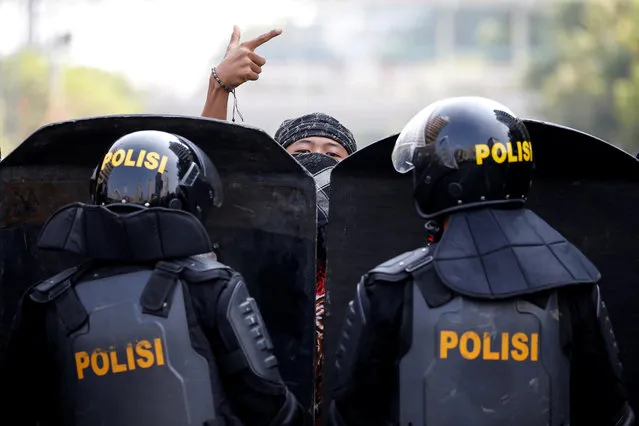 A protester gestures as mobile brigade (Brimob) police officers stand guard at a barricade during a protest near the Election Supervisory Agency (Bawaslu) headquarters in Jakarta, Indonesia, May 22, 2019. (Photo by Willy Kurniawan/Reuters)