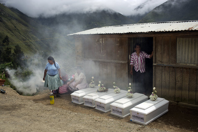In this March 29, 2016 photo, villagers gather next to coffins holding the remains of their loved ones, who were slain more than two decades ago by Shining Path rebels, before burying them in the cemetery in Ccano, a village in the Huanta area of Ayachcuo department, Peru. In  Ccano, many peasants worked with the military to fight the rebels, and the Shining Path stormed a church here in retaliation, killing everyone praying inside in 1991. (Photo by Rodrigo Abd/AP Photo)