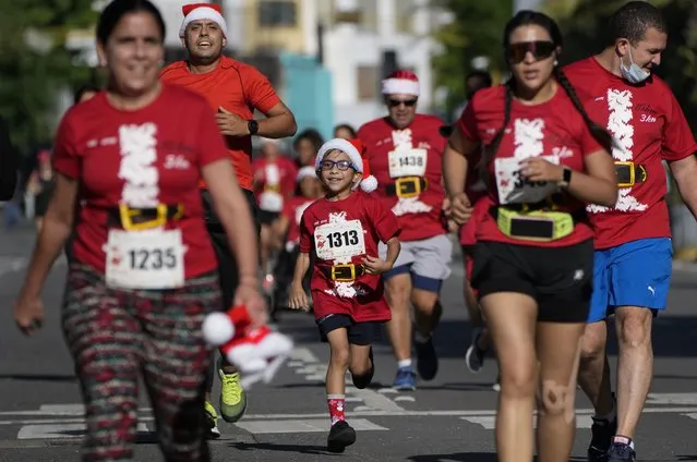 Runners participate in the Santa Run 10K race in Caracas, Venezuela, Sunday, December 19, 2021. This is the first Santa Run since the beginning of the pandemic. (Photo by Ariana Cubillos/AP Photo)
