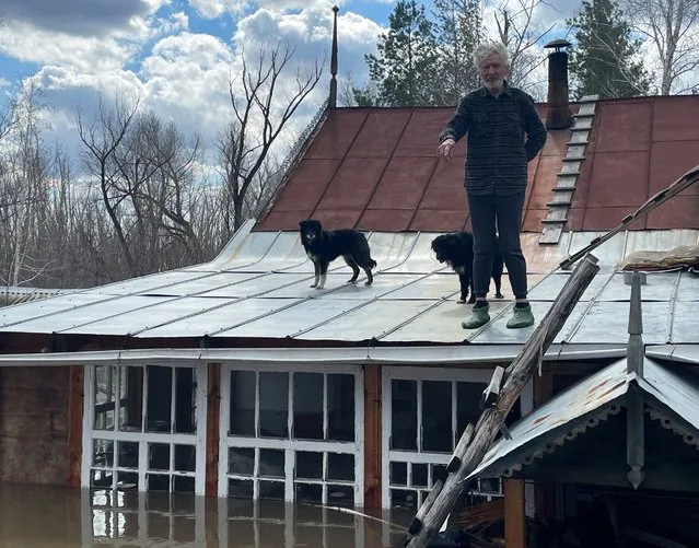 Artist Nikolai Kryuchkov stands on the roof of his flooded house in Orenburg, Russia, on April 13, 2024. (Photo by Alexander Reshetnikov/Reuters)