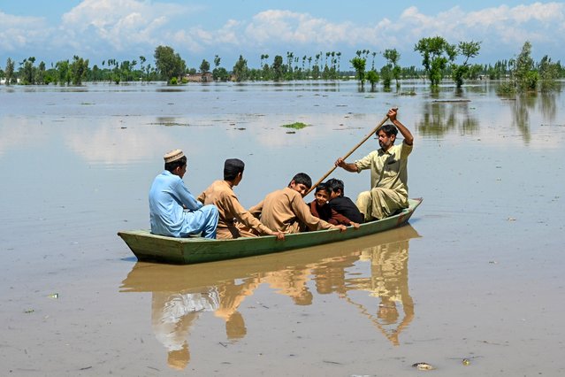 People ride a boat across a flooded area after heavy rains in Nowshera district, Khyber-Pakhtunkhwa province on April 16, 2024. At least 41 people have died in storm-related incidents across Pakistan since Friday, including 28 killed by lightning, officials said on April 15. (Photo by Abdul Majeed/AFP Photo)