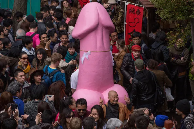 People pose for photos in front of a large pink phallic-shaped “Mikoshi” during Kanamara Matsuri (Festival of the Steel Phallus) on April 6, 2014 in Kawasaki, Japan. The Kanamara Festival is held annually on the first Sunday of April. The pen*s is the central theme of the festival, focused at the local pen*s-venerating shrine which was once frequented by prostitutes who came to pray for business prosperity and protection against sexually transmitted diseases. (Photo by Chris McGrath/Getty Images)