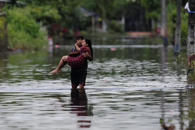 A man carries his wife on a flooded street after heavy rainfall in Milagro, Ecuador April 1, 2017. (Photo by Henry Romero/Reuters)