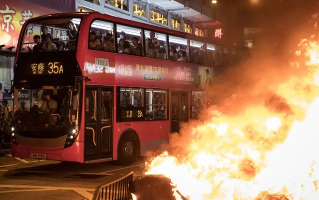 Passengers look out from a bus at a burning barricade lit by pro-democracy protesters during a protest gathering in front of Mong Kok police station on September 22, 2019 in Hong Kong, China. Pro-democracy protesters have continued demonstrations across Hong Kong, calling for the city's Chief Executive Carrie Lam to immediately meet the rest of their demands, including an independent inquiry into police brutality, the retraction of the word “riot” to describe the rallies, and genuine universal suffrage, as the territory faces a leadership crisis. (Photo by Chris McGrath/Getty Images)