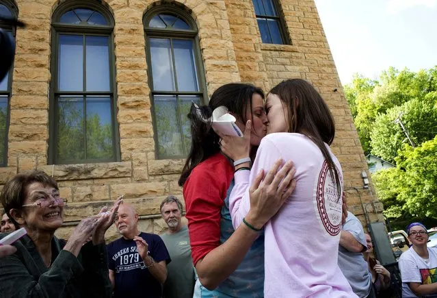 Jennifer Rambo, right, kisses her partner Kristin Seaton following their marriage ceremony in front of the Carroll County Courthouse as Sheryl Maples, far left, the lead attorney who filed the Wright v. the State of Arkansas lawsuit, looks on in Eureka Springs, Ark., on May 10, 2014. Rambo and Seaton were the first same-s*x couple to be granted a marriage license in Eureka Springs after a judge overturned Amendment 83, which banned same-s*x marriage in the state of Arkansas. (Photo by Sarah Bentham/Associated Press)