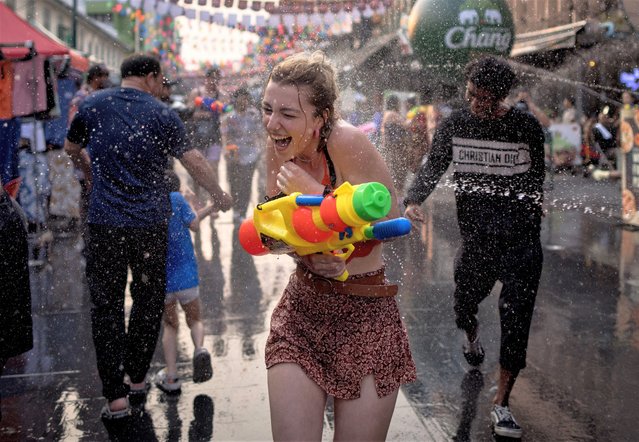 A woman is soaked as she runs down the street as revellers take part in a water fight on Khao San road on the eve of Thai New Year, locally known as Songkran, in Bangkok on April 12, 2023. (Photo by Jack Taylor/AFP Photo)