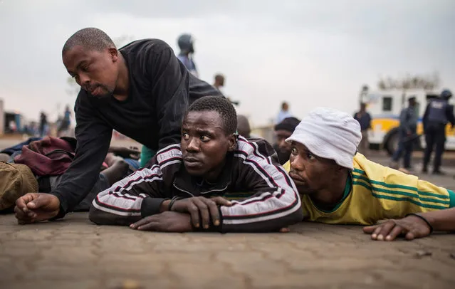 A group of men can be seen laying on the ground after being arrested  by members of the Ekurhuleni Metropolitan Police in Johannesburg Katlehong Township, during a new wave of anti-foreigner violence on September 5, 2019. Tensions eased between twin African powerhouses South Africa and Nigeria on September 5, after Pretoria temporarily closed its diplomatic missions in the rival state following a wave of attacks on foreign-owned stores there that claimed 10 lives. (Photo by Guillem Sartorio/AFP Photo)