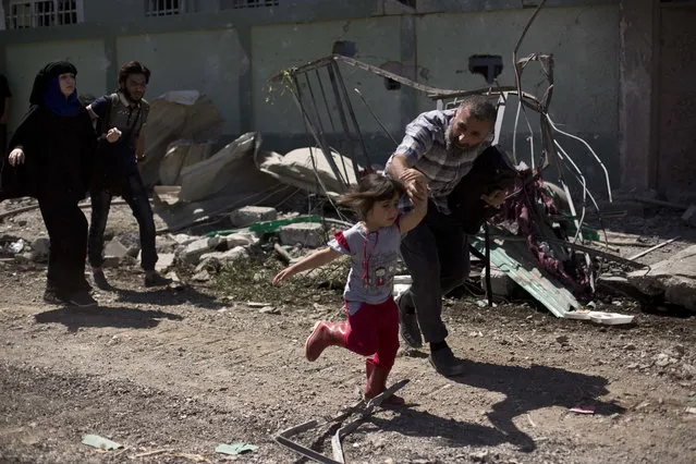 A man rushes his daughter to safety while fleeing the al-Rifai neighborhood as Iraqi special forces battle Islamic State militants, in western Mosul, Iraq, Wednesday, May 17, 2017. (Photo by Maya Alleruzzo/AP Photo)