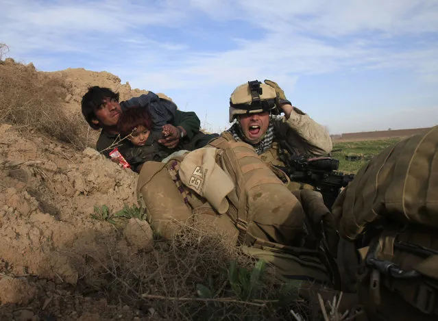 U.S. Marine Lance Corporal Chris Sanderson, 24, from Flemington, New Jersey shouts as he tries to protect an Afghan man and his child after Taliban fighters opened fire in the town of Marjah, in Nad Ali district, Helmand province, February 13, 2010. (Photo by Goran Tomasevic/Reuters)