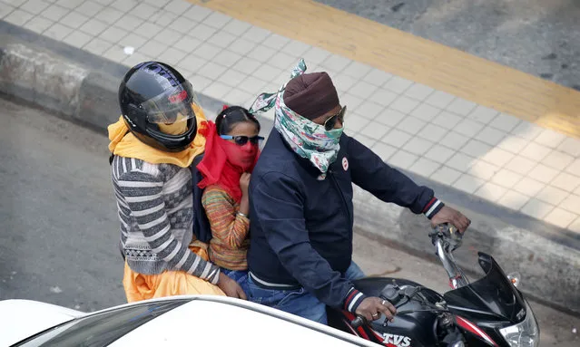 A family covers their face with clothe to save themselves from pollution as they ride on a motorcycle in New Delhi, India, Tuesday, November 12, 2019. A thick haze of polluted air is hanging over India's capital, with authorities trying to tackle the problem by sprinkling water to settle dust and banning some construction. The air quality index exceeded 400, about eight times the recommended maximum. (Photo by Manish Swarup/AP Photo)