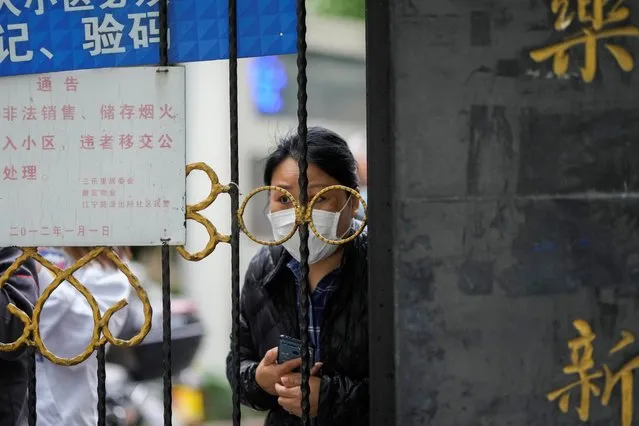 A resident waiting for a food delivery looks out from behind a gate blocking an entrance to a residential area under lockdown amid the coronavirus disease (COVID-19) pandemic, in Shanghai, China on April 13, 2022. (Photo by Aly Song/Reuters)
