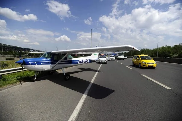 A taxi passes a small aircraft after it made an emergency landing on a busy highway in the outskirts of Budapest, Hungary, Monday, May 30, 2016. An official from a local airport says the Cessna took off on a training flight with two people on board and was forced to land because of engine failure. No injuries were reported. (Photo by Zoltan Mihadak/MTI via AP Photo)