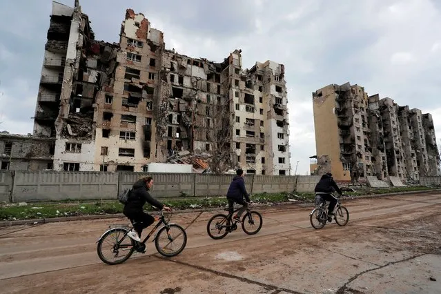 People ride bicycles near residential buildings heavily damaged during Ukraine-Russia conflict in the southern port city of Mariupol, Ukraine on April 22, 2022. (Photo by Alexander Ermochenko/Reuters)