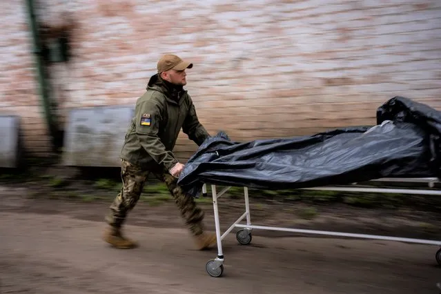 Darrell Loveless works moving dead bodies from refrigerated trucks to the morgue in Bucha, on the outskirts of Kyiv, Monday, April 25, 2022. (Photo by Emilio Morenatti/AP Photo)
