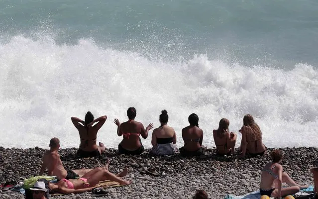 People sit on the beach along the Promenade Des Anglais after authorities closed beaches because of strong wind and waves as summer temperatures in the area rose to 34 degrees Celsius (93.2 Fahrenheit) in Nice, France, July 29, 2015. (Photo by Eric Gaillard/Reuters)