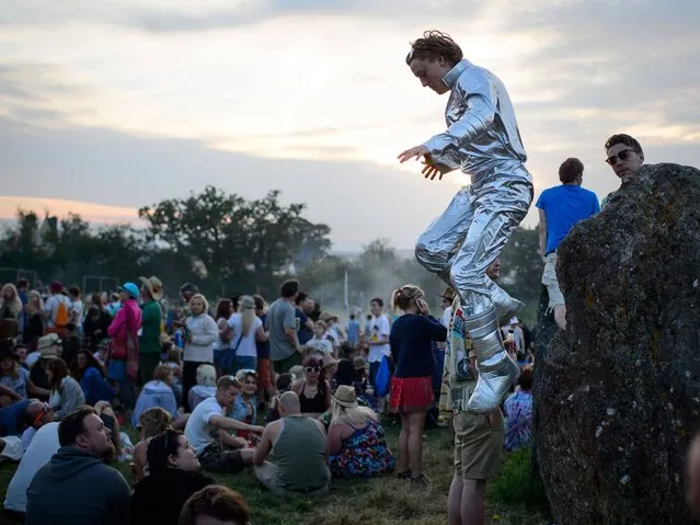 A man in a spacesuit jumps from one of the standing stones in the stone circle, as revelers gather ahead of this weekends Glastonbury Festival of Music and Performing Arts on Worthy Farm in Somerset. (Photo by Leon Neal/AFP Photo)