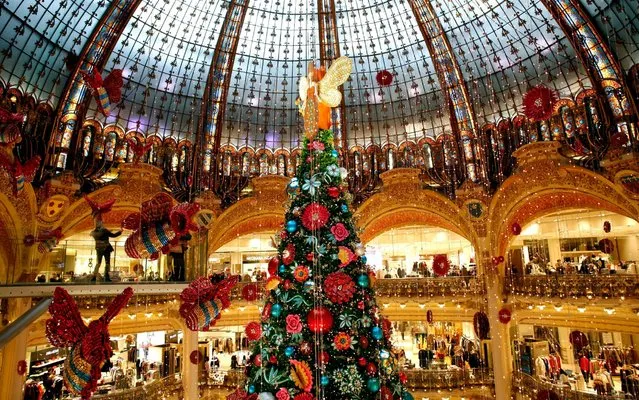 A giant christmas tree stands in the center of the Galeries Lafayette department store in Paris, Thursday, December 19, 2019. (Photo by Thibault Camus/AP Photo)