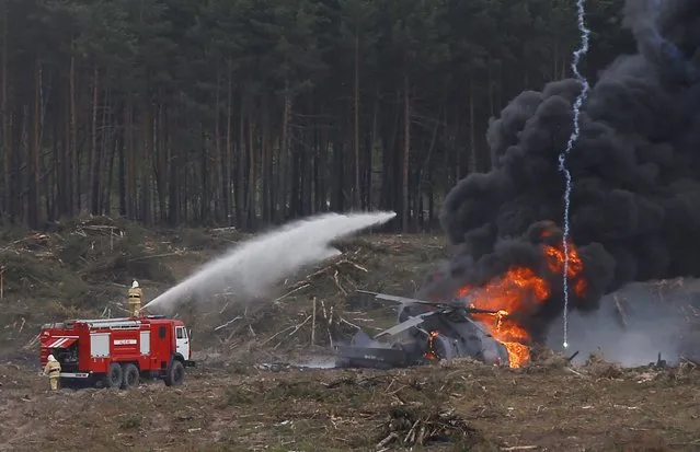 Firefighters work to extinguish fire, which overtook a Mi-28N from the Berkuty (Golden Eagles) helicopter display team after a hard touchdown during the “Aviadarts” military aviation competition at the Dubrovichi range near Ryazan, Russia, August 2, 2015. (Photo by Maxim Shemetov/Reuters)