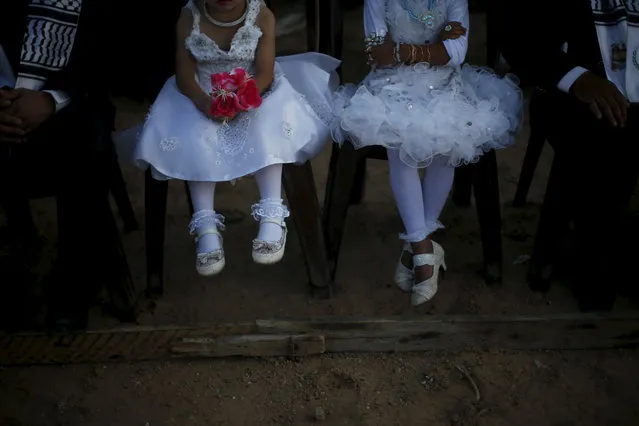 Girls accompany grooms as they sit separate from the brides during a mass wedding for 150 couples in Beit Lahiya town in the northern Gaza Strip, July 20, 2015. (Photo by Suhaib Salem/Reuters)