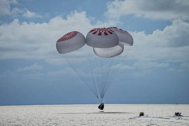 In this image taken provided by SpaceX, a capsule carrying four people parachutes into the Atlantic Ocean off the Florida coast, Saturday, September 18, 2021. The all-amateur crew was the first to circle the world without a professional astronaut. (Photo by SpaceX via AP Photo)