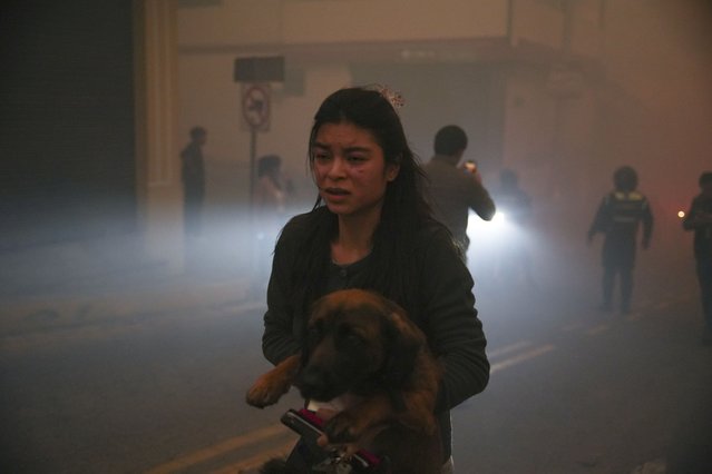 A resident carries a dog amid smoke from fires in a forested area in the Guapulo neighborhood of Quito, Ecuador, Tuesday, September 24, 2024. (Photo by Carlos Noriega/AP Photo)