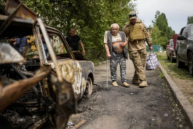 A volunteer helps a man leaving his home in a building damaged by an overnight missile strike, in Sloviansk, Ukraine, Tuesday, May 31, 2022. (Photo by Francisco Seco/AP Photo)