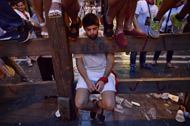 A reveller sleeps while waiting for the start of the second running of the bulls at the San Fermin Festival, in Pamplona, northern Spain, Saturday, July 8, 2017. Revellers from around the world flock to Pamplona every year to take part in the eight days of the running of the bulls. (Photo by Alvaro Barrientos/AP Photo)