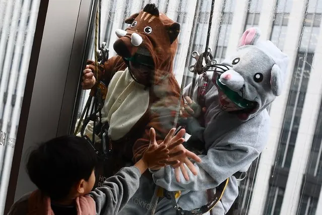 Workers wearing a pig and rat costume clean windows on a building in Tokyo on December 19, 2019. Much of Asia and the world celebrated the Lunar New Year of the Pig in 2019 and will welcome in the Year of the Rat in early 2020. (Photo by Charly Triballeau/AFP Photo)