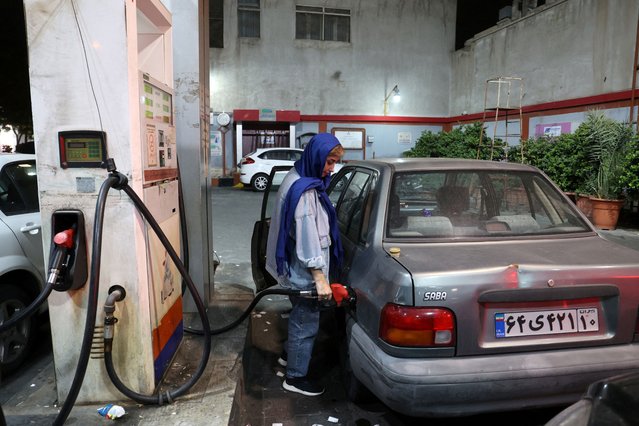 An Iranian woman fills her car with fuel at a gas station, after the IRGC attack on Israel, in Tehran, Iran, on October 1, 2024. (Photo by Majid Asgaripour/WANA (West Asia News Agency) via Reuters)