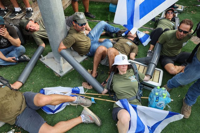 Activists of the "Brothers in Arms" group use arm tubes to form a chain blocking the main entrance of the “Kirya”, the Israeli army headquarters in the coastal city of Tel Aviv, during a 'day of resistance' to protest the government's judicial overhaul bill, on July 18, 2023. The proposals have divided the nation and triggered one of the biggest protest movements in Israel's history since being unveiled in January by the hard-right government of Prime Minister Benjamin Netanyahu. (Photo by Jack Guez/AFP Photo)