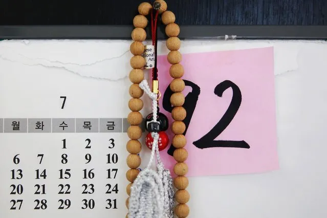 A Buddhist rosary hangs over a calendar and a piece of paper on which South Korean former “comfort woman” Park Ok-sun's current Korean nominal age “92” is written, in her room at the “House of Sharing”, a special shelter for former “comfort women”, in Gwangju, South Korea July 24, 2015. (Photo by Kim Kyung-Hoon/Reuters)