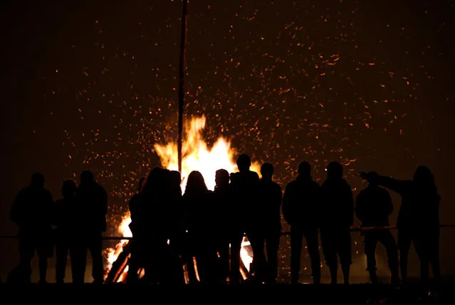 People looking at a bonfire during the traditional San Juan's (Saint John) night in Gijon, northern Spain, June 24, 2016. (Photo by Eloy Alonso/Reuters)