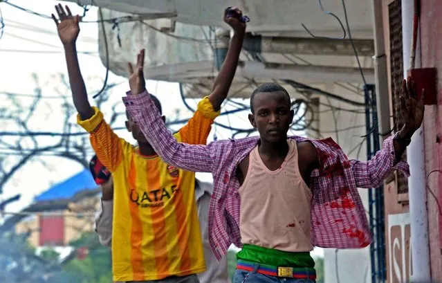 A man covered with blood runs away from the scene of a car bomb attack claimed by Al-Qaeda-affiliated Shabaab militants, which killed at least 5 people, on the Naasa Hablood hotel in Mogadishu on June 25, 2016. The hotel in southern Mogadishu is often used by politicians and members of the Somali diaspora visiting the city. The attack came just three weeks after another assault quickly claimed by the Al-Qaeda-linked Shabaab group on the city's Ambassador hotel left 10 dead including two lawmakers when a huge car bomb ripped the front off the six-storey building. (Photo by Mohamed Abdiwahab/AFP Photo)
