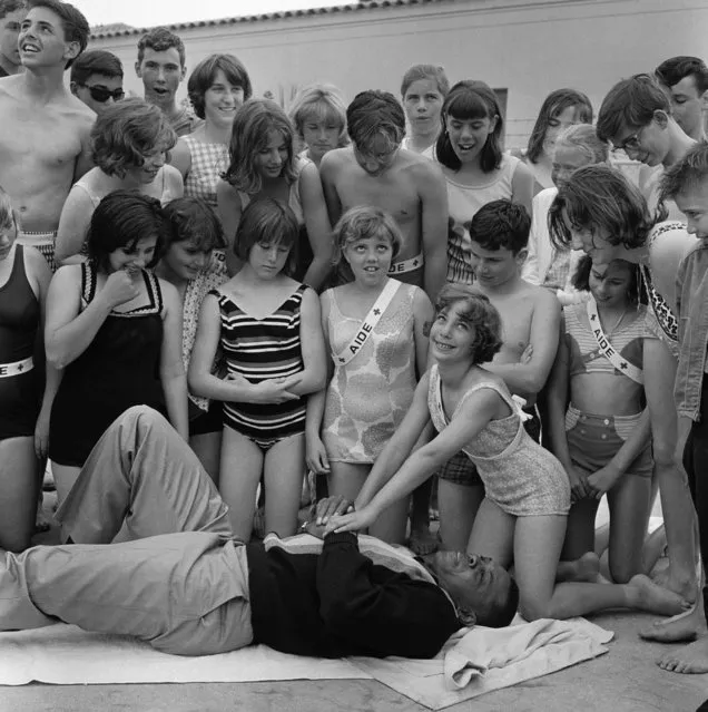 San Francisco centerfielder Willie Mays visited the Red Cross Volunteer Swim Aide School June 16, 1964 at Fleishhacker Pool in San Francisco and became the subject of a demonstration in artificial respiration. Shown demonstrating the rescue technique (CPR) as dozens of other youngsters watch is Joan Cappel. 11. (Photo by Robert W. Klein/AP Photo)