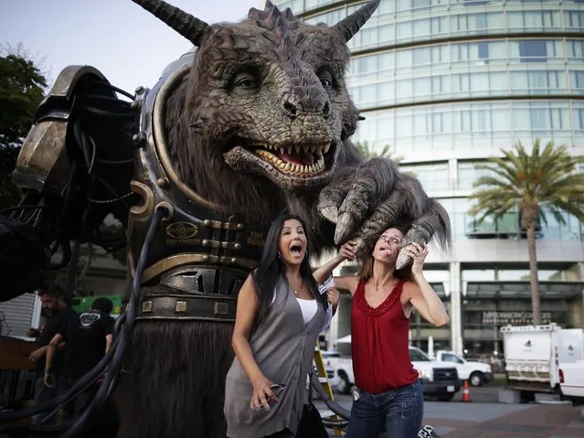Piper Rhodes, right, and Rosana Olson joke with a creation from Legacy Effects, behind, during Comic-Con Thursday, July 24, 2014, in San Diego. Thousands of fans with four-day passes to the sold-out pop-culture spectacular flocked to the event Thursday, many clad in costumes. (Photo by AP Photo)