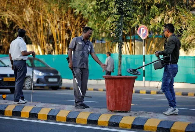 Members of a bomb disposal squad from Gujarat Police scan a plant pot on a road divider along a route that U.S. President Donald Trump and India's Prime Minister Narendra Modi will be taking during Trump's upcoming visit, in Ahmedabad, February 18, 2020. (Photo by Amit Dave/Reuters)