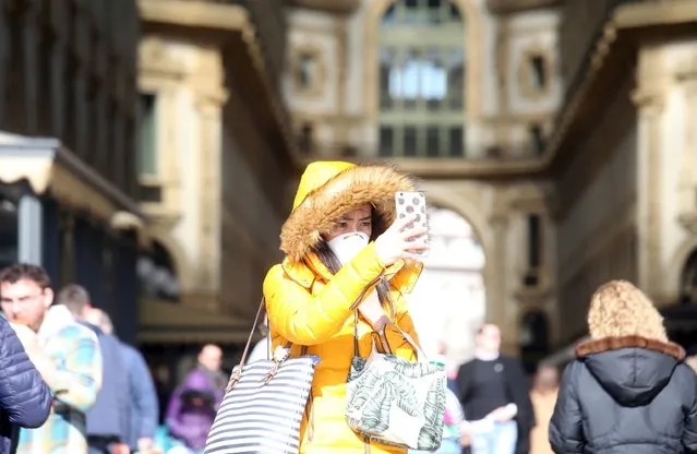 A woman wearing a protective face mask uses a mobile phone, in the center of Milan, northern Italy, 24 February 2020. Italian authorities announced on the day that there are over 200 confirmed cases of COVID-19 disease in the country, with at least five deaths. Precautionary measures and ordinances to tackle the spreading of the deadly virus included the closure of schools, gyms, museums and cinemas in the affected areas in northern Italy. (Photo by Matteo Bazzi/EPA/EFE)