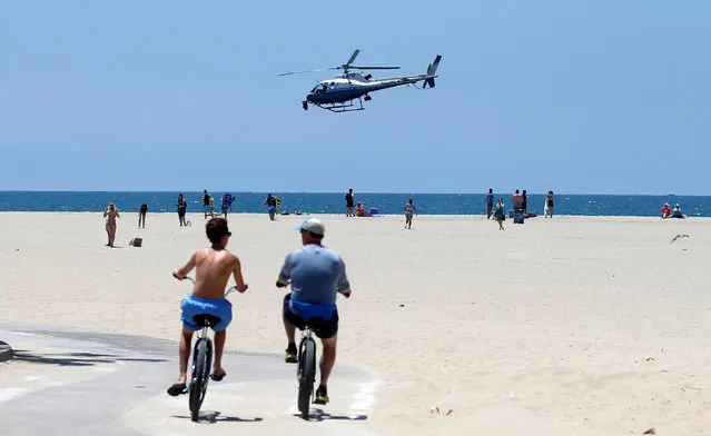 A Los Angeles Police Department helicopter flies low over the beach in the Venice neighborhood of Los Angeles, California U.S., July 6, 2016. (Photo by Mario Anzuoni/Reuters)