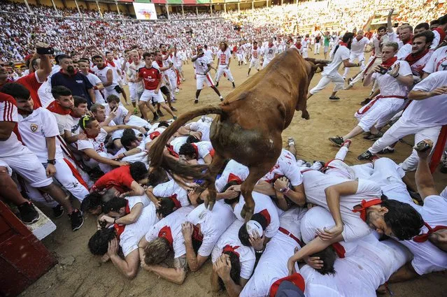 A cow jumps over revelers during a cow festival at the end of the second running of the bulls at the San Fermin Festival in Pamplona, northern Spain, Friday, July 8, 2016. (Photo by Alvaro Barrientos/AP Photo)
