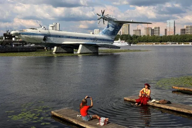 Women rest on a pier at the Moscow Canal, with the Soviet-made ekranoplan Orlyonok, which is a naval craft and a ground-effect vehicle in the Russian Navy maritime history complex, seen in the background in Moscow, Russia on July 25, 2022. (Photo by Evgenia Novozhenina/Reuters)
