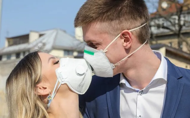 Lithuanian groom Dainius and his bride Ramune pose for the photographer, wearing protective masks against the new coronavirus after their wedding ceremony in Vilnius, Lithuania on March 28, 2020. (Photo by Petras Malukas/AFP Photo)