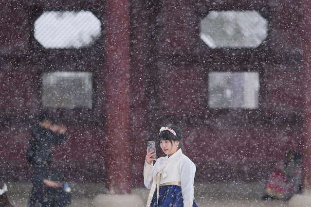Chan Yian from Taiwan holds her smartphone in snow at the Gyeongbok Palace, one of South Korea's well-known landmarks, in Seoul, South Korea, Wednesday, November 27, 2024. (Photo by Lee Jin-man/AP Photo)