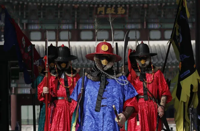 Officials wearing traditional guard uniforms and protective face masks walk at the Gyeongbok Palace, the main royal palace during the Joseon Dynasty and one of South Korea's well known landmarks in Seoul, South Korea, Saturday, February 29, 2020. The coronavirus outbreak's impact on the world economy grew more alarming on Saturday, even as President Donald Trump denounced criticisms of his response to the threat as a “hoax” cooked up by his political enemies. (Photo by Lee Jin-man/AP Photo)