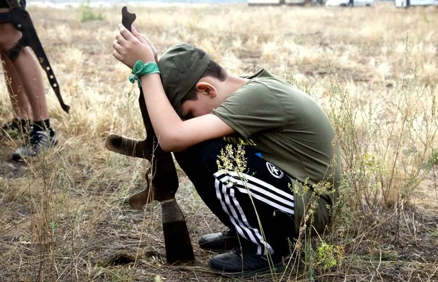 A boy has a rest at a military training ground of Ukraine's National Guard where professional servicemen are teaching children to operate weapons outside the village of Stare, the Kiev region, Ukraine, Saturday, August29, 2015. (Photo by Efrem Lukatsky/AP Photo)