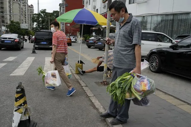 Residents carry their fresh produces after shopping in Beijing, Monday, August 15, 2022. (Photo by Ng Han Guan/AP Photo)
