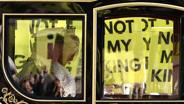 Britain's King Charles III and Britain's Queen Camilla travel in the Diamond Jubilee State Coach past protesters holding “Not My King” placards, from the anti-monarchy group Republic as they demonstrate ahead of the State Opening of Parliament, opposite the Houses of Parliament in London on November 7, 2023. (Photo by Henry Nicholls/AFP Photo)