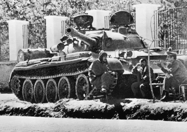 Tank crewmen bask in the sunshine beside their Soviet-made tank after taking station outside the Soviet Embassy in Kabul, Afghanistan, May 3, 1978. The former Soviet Union marched into Afghanistan on Christmas Eve, 1979, claiming it was invited by the new Afghan communist leader, Babrak Karmal, setting the country on a path of 40 years of seemingly endless wars and conflict. After the Soviets left in humiliation, America was the next great power to wade in. (Photo by AP Photo, File)