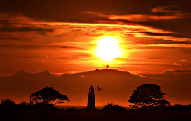 The sun rises over Whitley Bay with the top of St Mary's lighthouse visible, as hot and humid air is expected to be pushed into northern Europe this weekend, including Britain, creating a “Spanish Plume” on August 21, 2015. (Photo by Owen Humphreys/PA Wire)